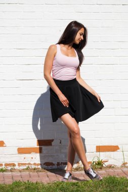 Tam vücut kadın. Mutlu güzel genç esmer modelinde siyah etek, beyaz duvara karşı