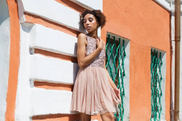 Portrait of an African model woman in pink dress, summer street outdoor