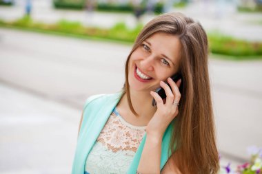 Güzel genç esmer kadın telefon, yaz sokak açık havada ederken