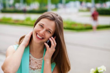 Güzel genç esmer kadın telefon, yaz sokak açık havada ederken