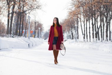 Tam vücut. Genç güzel esmer kadın kırmızı paltolu kış park üzerinde poz. Şık sıcak giysiler giyen modeli.