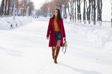 Tam vücut. Genç güzel esmer kadın kırmızı paltolu kış park üzerinde poz. Şık sıcak giysiler giyen modeli.