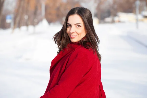 冬の公園でポーズの赤いコートで若い美しいブルネットの女性 スタイリッシュな暖かい服を着てモデル — ストック写真