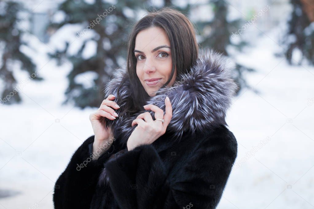 Young beautiful woman warms her palms with her breath in the frosty weather of her palms.