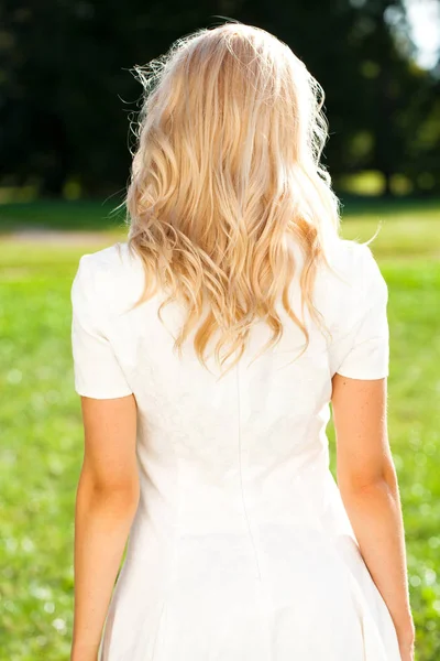 Female Long wavy blonde hair, rear view, summer street outdoors