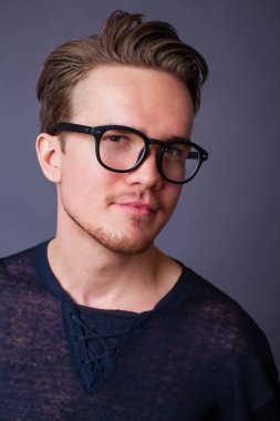 Karanlık bir arka plan üzerinde büyük gözlüklü genç bir adam portresi stüdyo