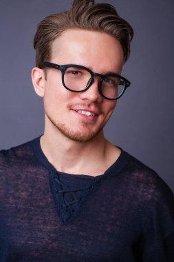 Karanlık bir arka plan üzerinde büyük gözlüklü genç bir adam portresi stüdyo