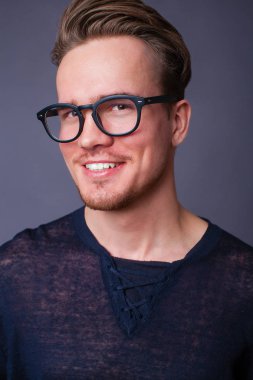 Karanlık bir arka plan üzerinde büyük gözlüklü genç bir adam portresi stüdyo