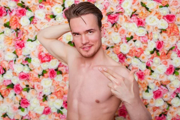 一个年轻的性感的家伙的肖像在花卉工作室墙的背景 — 图库照片