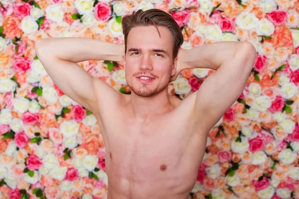花スタジオの壁の背景に若いセクシーな男の肖像 — ストック写真