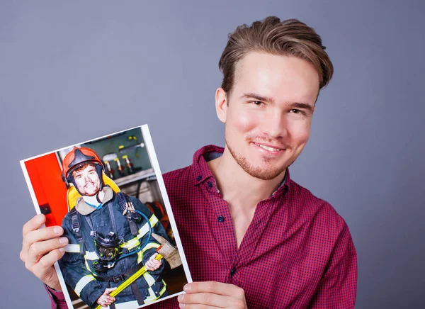 Молодой Парень Держит Свое Фото Изображением Пожарного — стоковое фото
