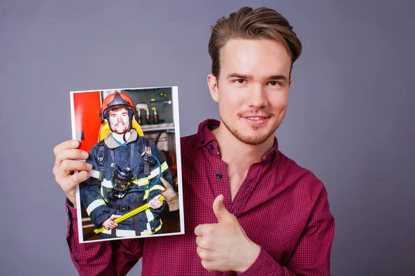 Joven Sostiene Foto Con Imagen Bombero —  Fotos de Stock