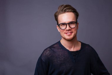 Karanlık bir arka plan üzerinde büyük gözlüklü genç bir adam portresi stüdyo