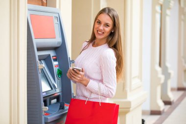 Genç güzel sarışın bir kadınla bir telefon alışveriş merkezi Atm arka planda olduğu