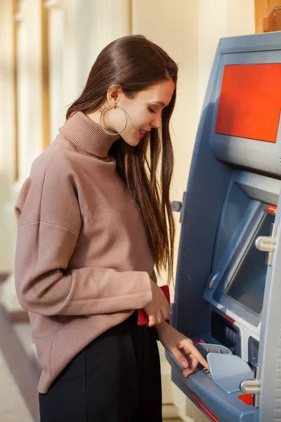 Happy brunette woman withdrawing money from credit card at ATM — Stock Photo, Image