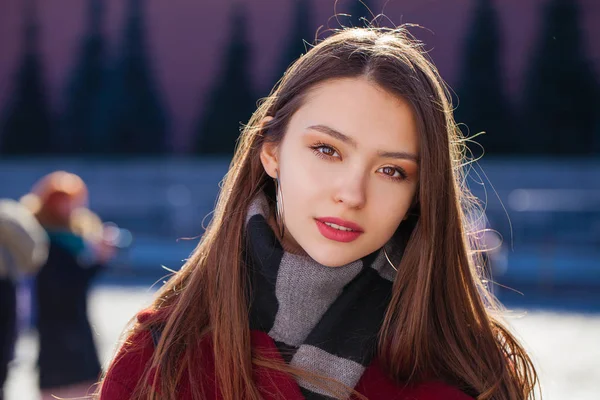 Mladá krásná brunetka žena v červeném kabátě pózuje na winter park — Stock fotografie