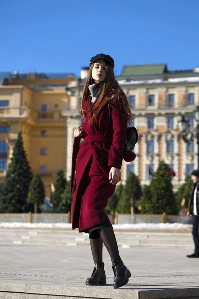 Vacker flicka i stilfull i en lång vinröd kappa — Stockfoto