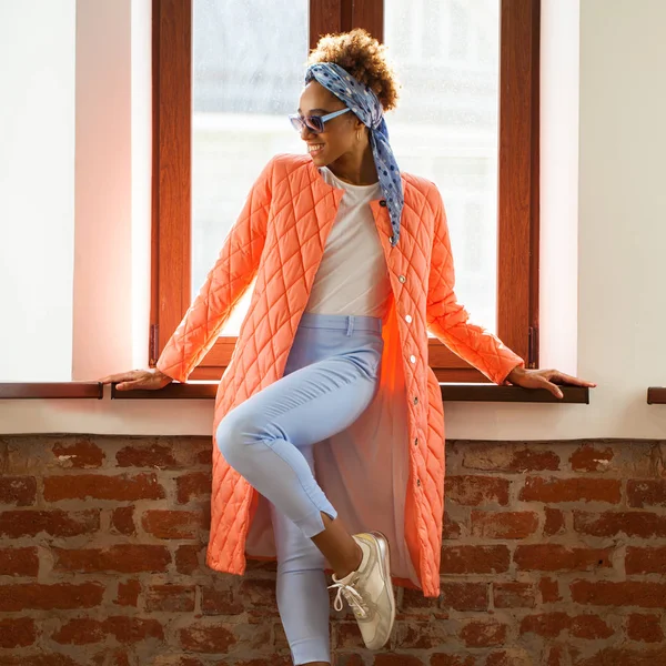 Африканская модель в оранжевой весенней куртке и голубых брюках — стоковое фото