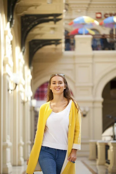 Молода жінка в жовтому пальто ходить в магазині — стокове фото