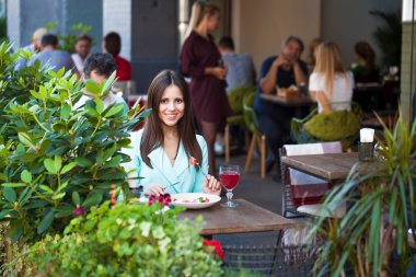 Genç güzel kadın bir kafede kahvaltı yapıyor