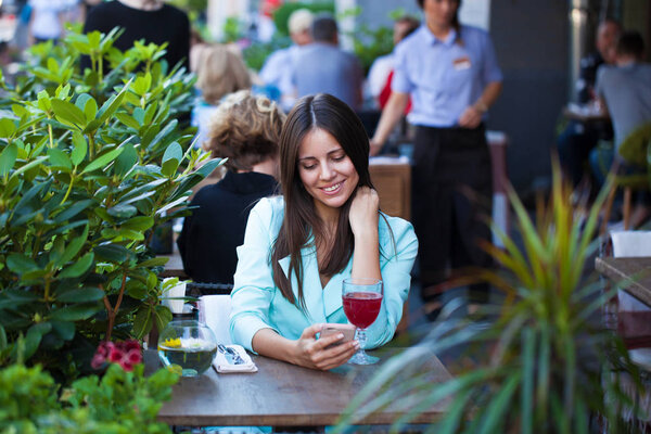 Elegant girl calling someone while resting in outdoor cafe with 