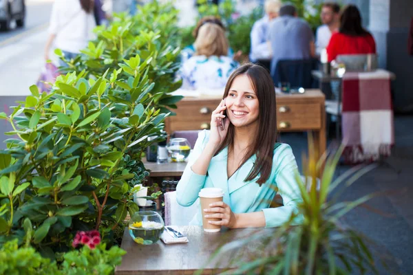 Elegante chica llamando a alguien mientras descansa en la cafetería al aire libre con —  Fotos de Stock