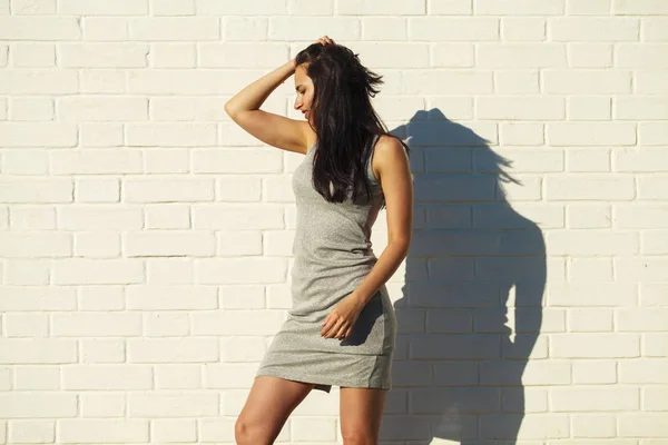 Hermosa mujer joven en vestido gris sexy, contra la pared blanca — Foto de Stock