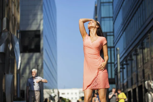 Ung vacker flicka poserar mot den blå himlen och höghus b — Stockfoto