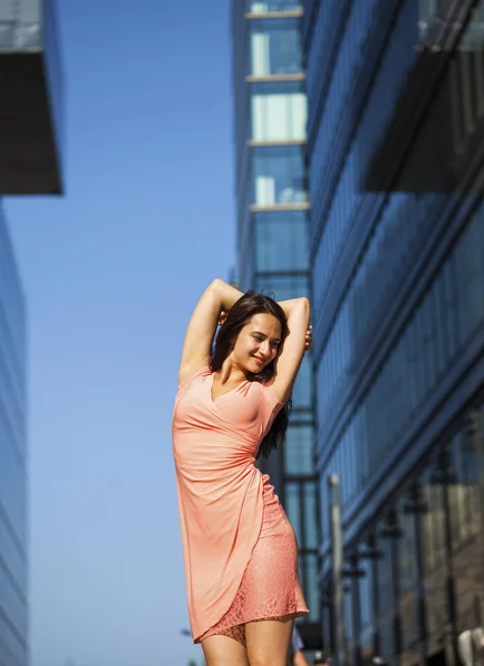 Jovem bela menina posando contra o céu azul e arranha-céus b — Fotografia de Stock