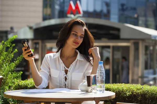 Elegant girl calling someone while resting in outdoor cafe with — Stock Photo, Image