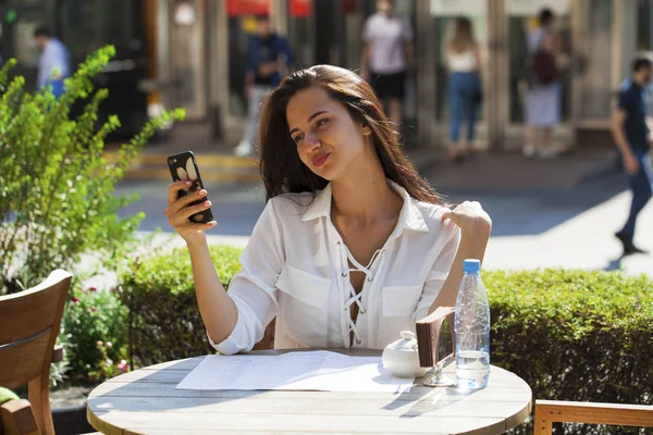 Elegante meisje iemand opbellen terwijl rusten op terras met — Stockfoto