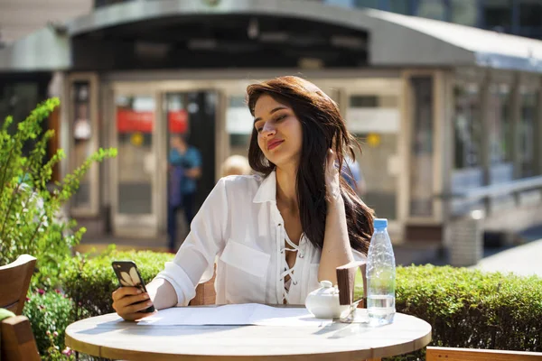 Elegante meisje iemand opbellen terwijl rusten op terras met — Stockfoto