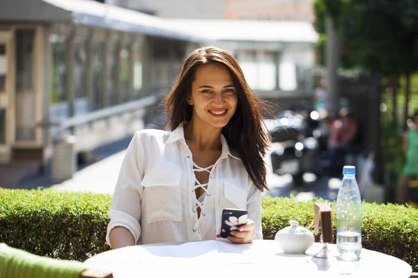 Menina elegante chamando alguém enquanto descansa no café ao ar livre com — Fotografia de Stock