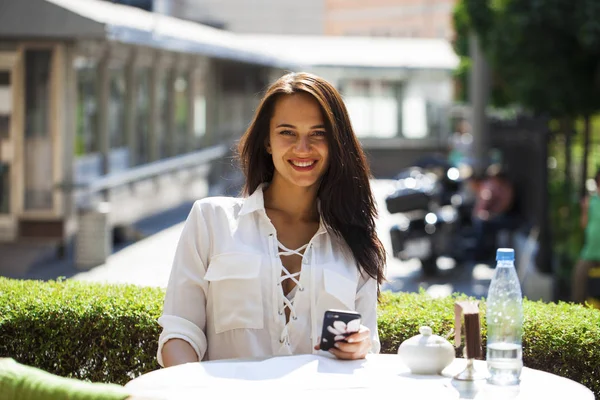 Elegante meisje iemand opbellen terwijl rusten op terras met — Stockfoto