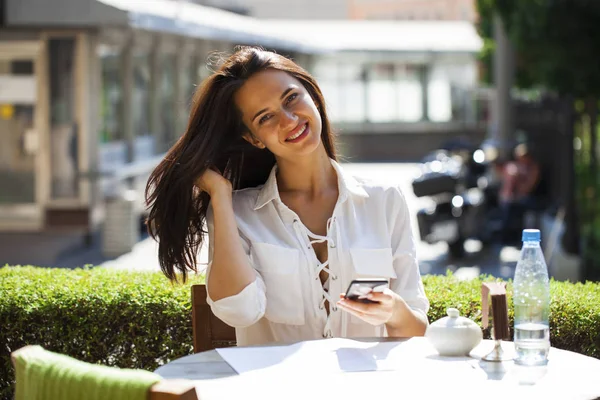 Elegantes Mädchen, das jemanden anruft, während es sich in einem Café im Freien mit — Stockfoto