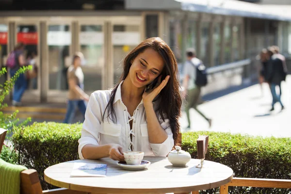 Elegante meisje iemand opbellen terwijl rusten op terras met — Stockfoto