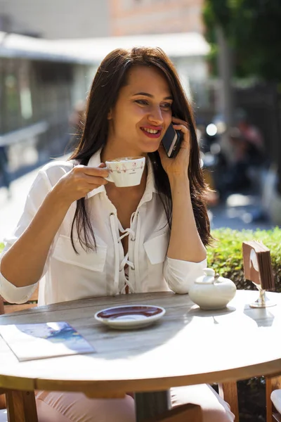 Élégante fille appelant quelqu'un tout en se reposant dans un café extérieur avec — Photo
