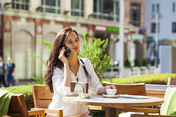 Elegante meisje iemand opbellen terwijl rusten op terras met — Stockfoto