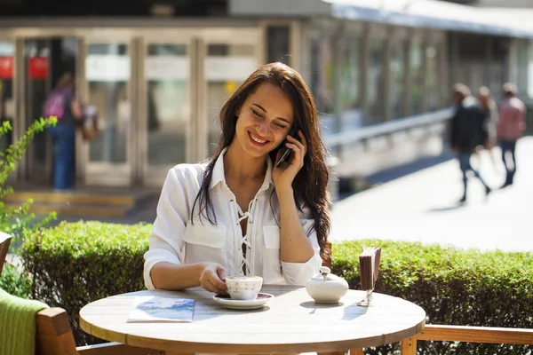 Elegantes Mädchen, das jemanden anruft, während es sich in einem Café im Freien mit — Stockfoto