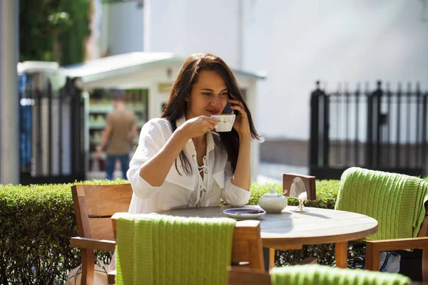 Menina elegante chamando alguém enquanto descansa no café ao ar livre com — Fotografia de Stock