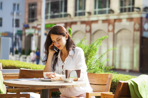 Elegant girl calling someone while resting in outdoor cafe with — Stock Photo, Image