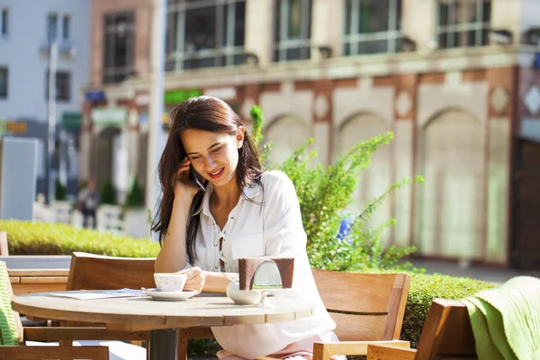 Eleganta tjej ringer någon medan de vilar i utomhus café med Royaltyfria Stockfoton