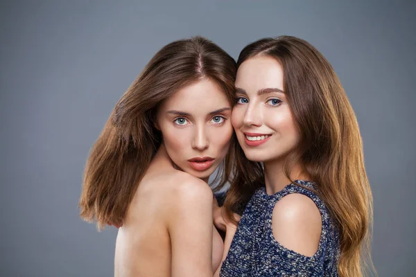 Dvě mladé modely izolované na šedém pozadí — Stock fotografie