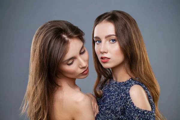 Twee jonge modellen geïsoleerd op een grijze achtergrond — Stockfoto