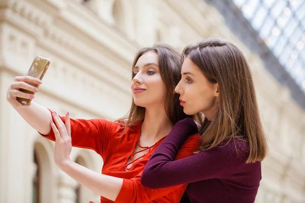 Two smiling women take a picture of herself with a smart phone — Stock Photo, Image