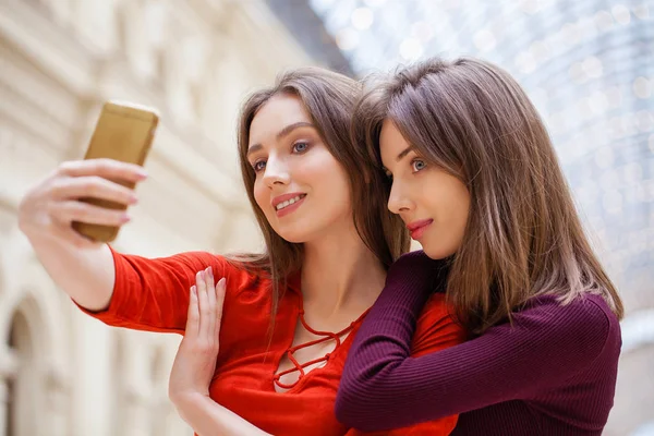 Dos mujeres sonrientes se toman una foto con un teléfono inteligente —  Fotos de Stock