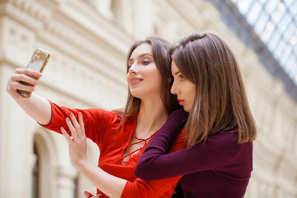 Dos mujeres sonrientes se toman una foto con un teléfono inteligente —  Fotos de Stock