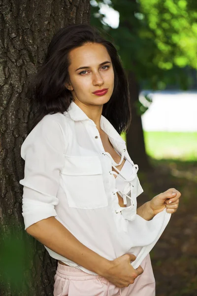 Mladá brunetka žena v letním parku — Stock fotografie