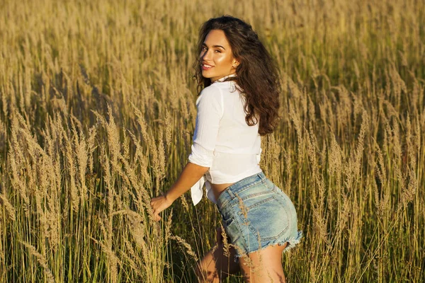 Jonge mooie brunette vrouw in een wit overhemd en blauwe denim s — Stockfoto