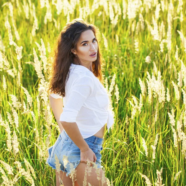 Jovem bela mulher morena em uma camisa branca e jeans azul s — Fotografia de Stock